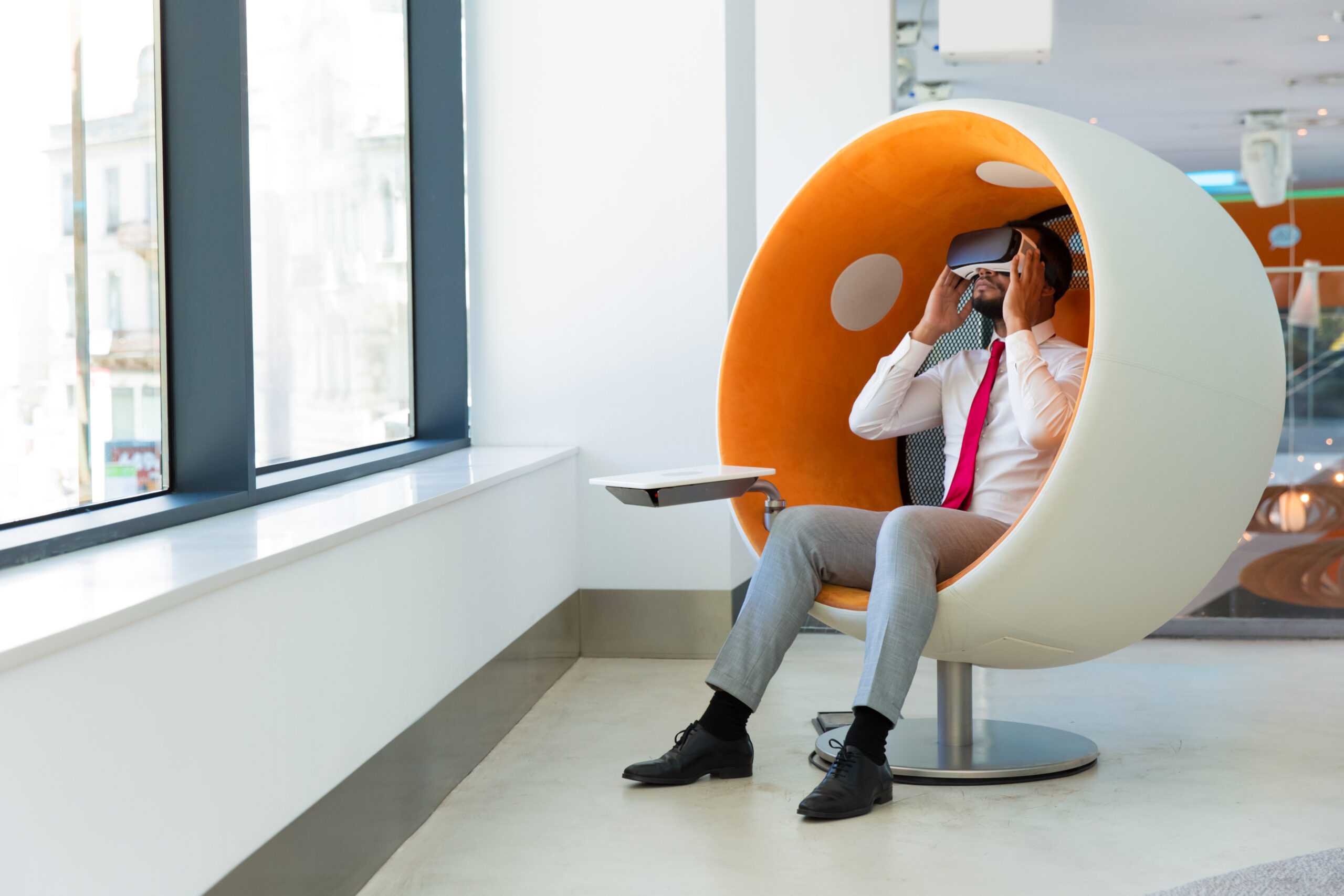 Business leader using VR goggles. Man wearing office clothes and virtual reality headset, sitting in interactive chair. Simulation concept